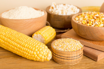 Maize products with fresh corn cobs on wooden table