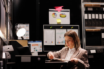 Bookkeeper reading management report in arhive room, working late at night at accountancy research....