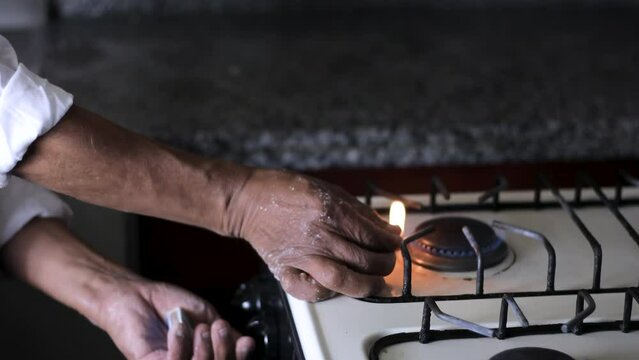 man's hands lighting a match to light the fire of a stove in a kitchen