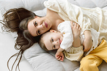 Top view of a beautiful woman and her cute little son smiling while lying on the floor. boy hug his mom