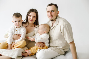 happy family of 4 standing over white background. Young couple with kids two boys