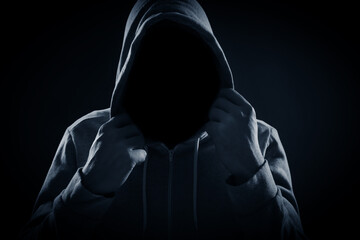 Anonymous man in hood on black background