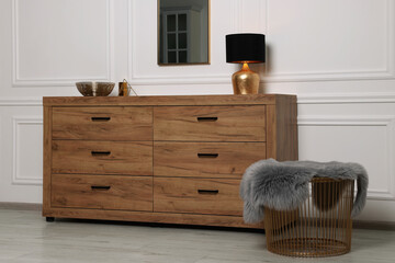 Stylish room interior with chest of drawers, mirror and decor elements