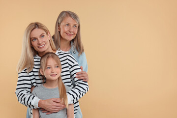 Three generations. Happy grandmother, her daughter and granddaughter on beige background, space for text