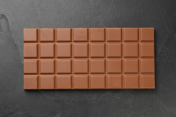 Tasty chocolate bar on grey table, top view