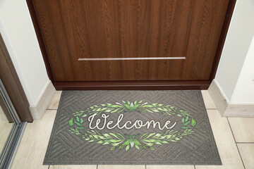 Beautiful doormat with word Welcome on floor near entrance