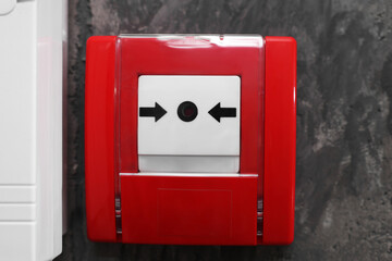 Fire alarm push button on grey wall