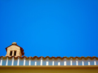 Fototapeta na wymiar Schornstein und gewelltes Hausdach ragen in den blauen Himmel von Sardinien