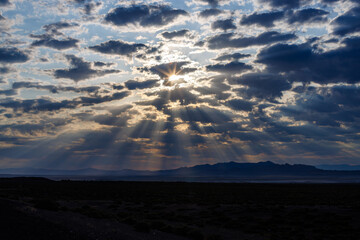 Cloudy sky with sun rays and mountains in the background
