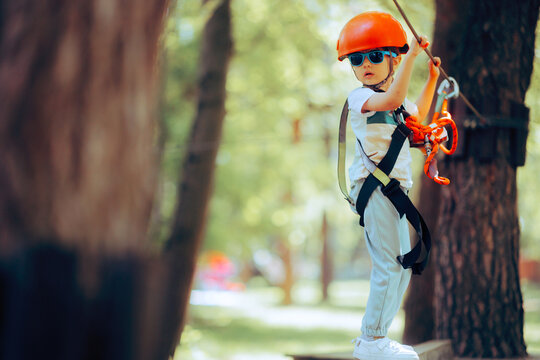 Little Girl Having Fun in a Rope Park Trail Facility. Happy little child enjoying climbing in an adventure park 
