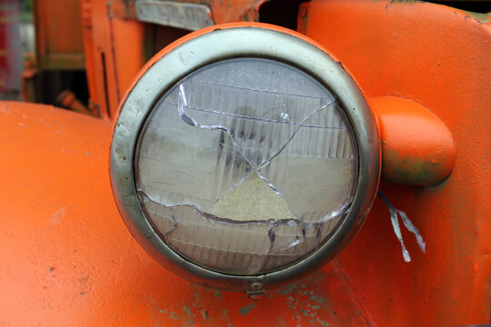 Broken headlight on an old orange truck vehicle