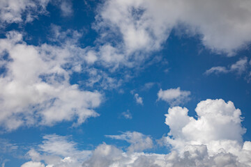 A horizontal shot of bright blue sky with puffy white clouds.
