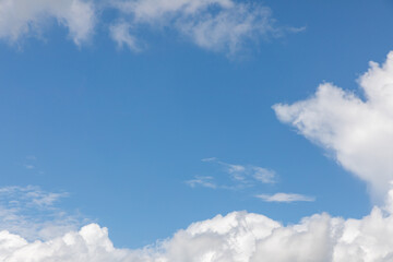A horizontal shot of bright blue sky with puffy white clouds.