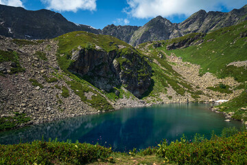View of the Dukka lake "Rybka" on the Malaya Dukka River on the slopes of the Arkasar ridge in the North Caucasus on a sunny summer day, Arkhyz, Karachay-Cherkessia, Russia © Ula Ulachka