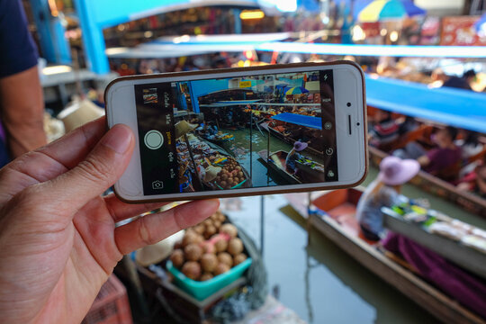 Woman hand take photo phone travel in damnoen saduak floating market sightseeing food and drink culture