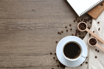Obraz na płótnie Canvas Coffee cup americano with roasted coffee bean, notebook on wooden background. Top view with copy space for your text