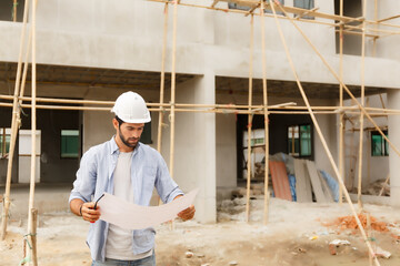 Young male architect, engineering consultant On a construction site holding a blueprint in hand Building inspector.