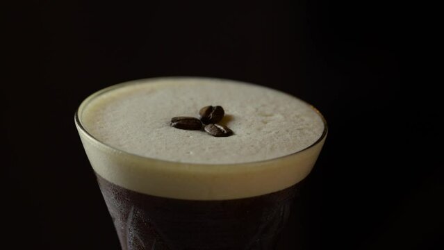 Coffee beans being placed as garnish on espresso martini cocktail