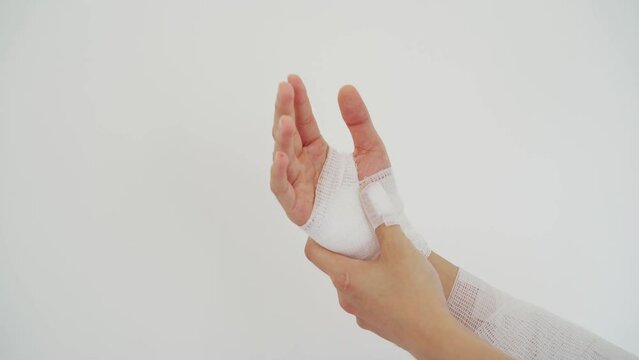 Young man with gauze bandage wrapped around injury hand on white background