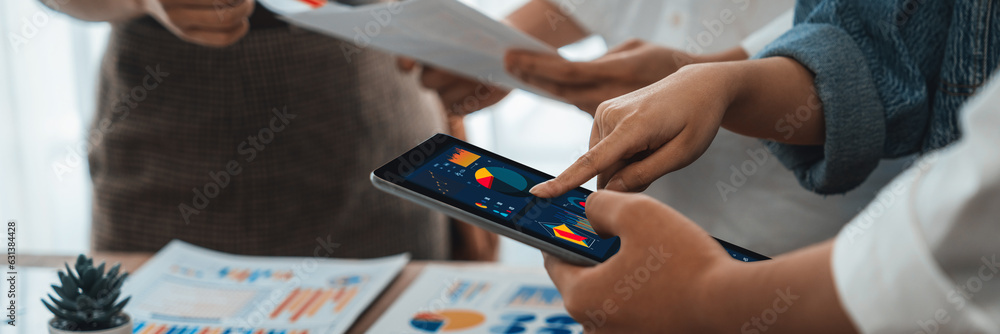 Poster Analyst team utilizing BI Fintech to analyze financial report with tablet over paper on table and analyzing BI power dashboard display on tablet screen for business insight. Panorama shot. Scrutinize