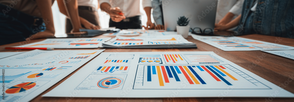 Leinwandbilder Focus panorama shot of chart and graph paper with blur analyst team utilize BI Fintech to analyze financial dashboard, brainstorm and analyzing report paper on table for business insight. Scrutinize