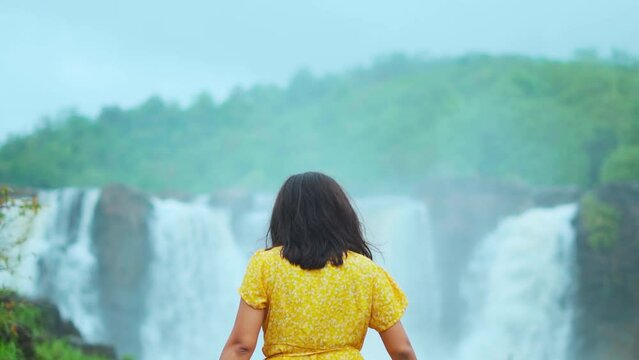Indian young woman walking and Gira waterfall in background at Waghai, Gujarat, India. Tourist enjoying vacation. Indian ethnic woman.