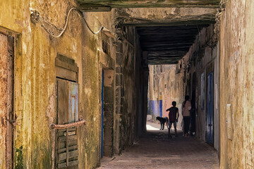 Narrow alley inside the Essaouira Medina, Morocco. Moroccan kid silhouette under a dark passage.