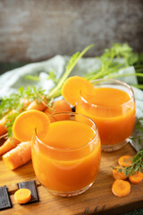 Carrot juice in a glass and fresh carrots with leaves on a stone table. Carrot healthy juice for detox. Healthy vegan vegetarian drink. Copy space.