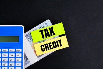 calculator, paper money and colored paper with the word Tax credit. tax credit concept