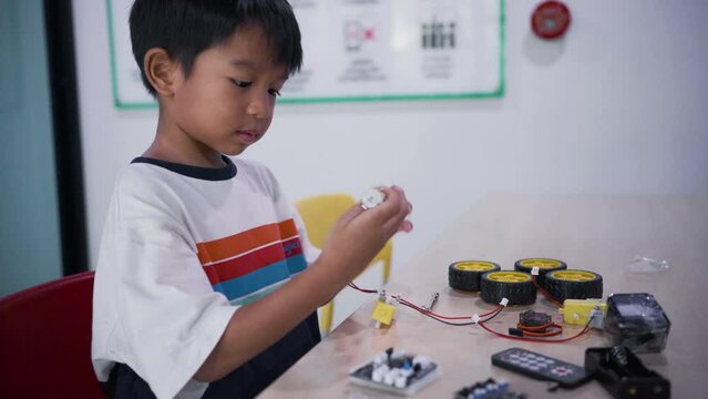 Asian  Student Boy Building Robot Vehicle In After School Computer Coding Class technology of robotics programing and STEM education concept.