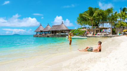 Man and Woman on a tropical beach in Mauritius, a couple on a honeymoon vacation in Mauritius on a sunny day with turqouse colored ocean and a white beach