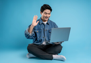Full body young  Asian man using laptop on blue background