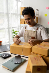 Male owner of an online store packs products into parcel boxes based on orders from online sales sites, packs products for delivery to addresses via private courier service. Product packaging concept.