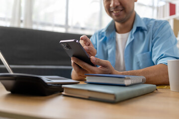 Asian man holding cell phone, he is texting via smartphone application talking to friends, using smartphone to send text messages over the internet. The concept of using technology in communication.