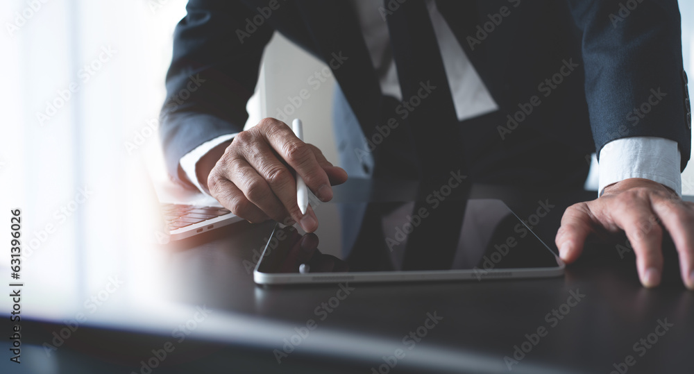 Aufkleber businessman using digital tablet surfing the internet and working on laptop computer on office desk.