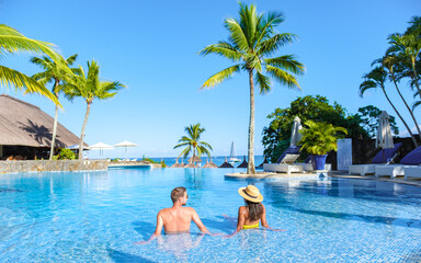 Man and Woman relaxing in a swimming pool, a couple on a honeymoon vacation in Mauritius tanning in...