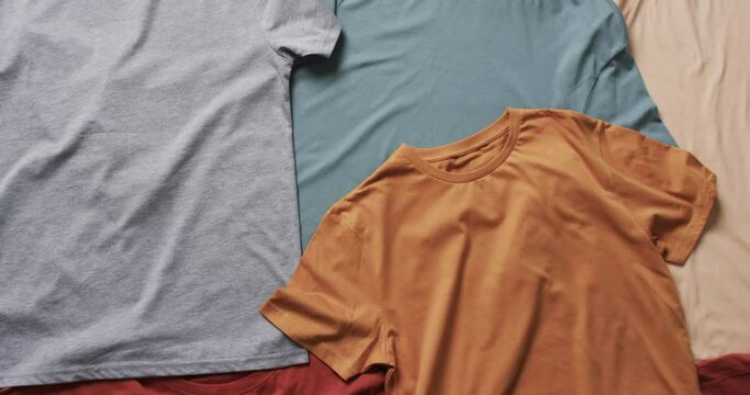 Video of flat lay of multi coloured t shirts with copy space on white background