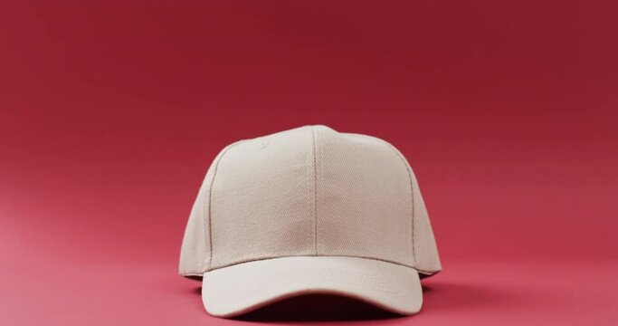 Video of beige baseball cap and copy space on red background