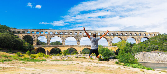 Pont du Gard and happy man tourist  jumping- tour tourism, travel, vacation in France- Gard