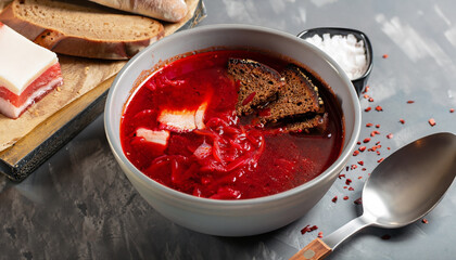 Delicious fresh red borscht, dark bread with lard and salt on kitchen table. Copy space.