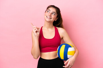 Young caucasian woman playing volleyball isolated on pink background pointing up a great idea