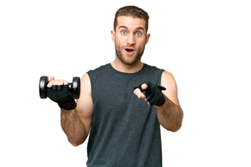 Young sport man making weightlifting over isolated chroma key background surprised and pointing front