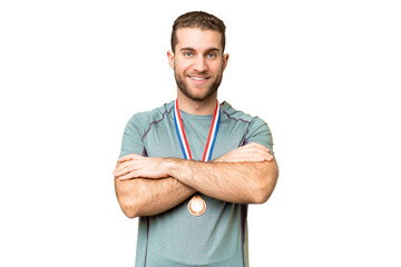 Young handsome blonde man with medals over isolated chroma key background keeping the arms crossed...