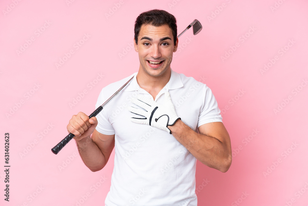 Sticker Young golfer player man isolated on pink background surprised and shocked while looking right