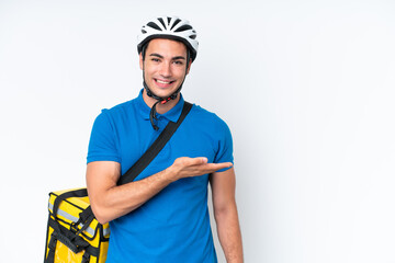 Young caucasian man with thermal backpack isolated on white background presenting an idea while looking smiling towards