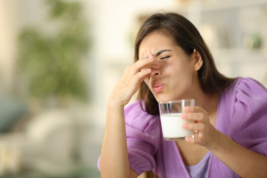 Woman smelling expired milk at home