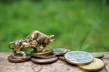 A figurine of a metal bull with a bunch of coins. Finance and economics.