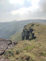 A breathtaking view from the summit of Baba Budan Giri mountain in Chikmagalur, Karnataka, India, showcasing rolling hills, lush greenery, and mist-covered peaks that define this stunning landscape.
