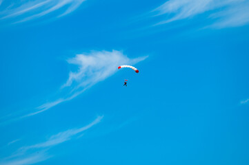 Parachutist with a white and red parachute against the blue sky