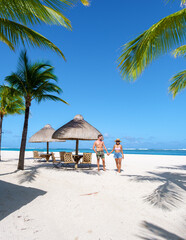 Man and Woman on a tropical beach with beach chairs and palm trees in Mauritius, a couple on a honeymoon vacation in Mauritius Le Morne Beach with Le Morne Mountain on the background
